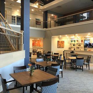 A modern, open-space restaurant with a two-story layout featuring multiple dining tables and comfortable seating.