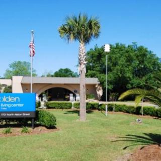 A hospital building with well-maintained landscaping and a prominent sign in front.