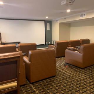 A cozy home theater room with leather seating and a large projector screen.