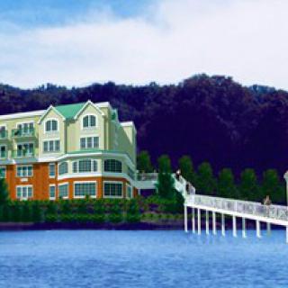 A scenic view of a building by the water with a bridge leading to it.