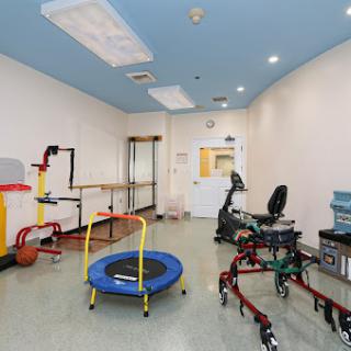 A well-equipped therapy room featuring a trampoline and various rehabilitation tools.