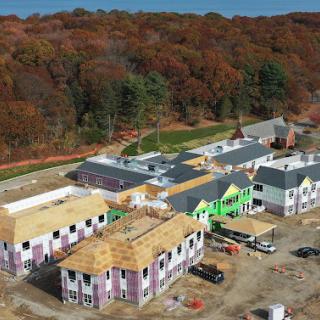 Aerial view of a housing development under construction amidst vibrant autumn foliage.