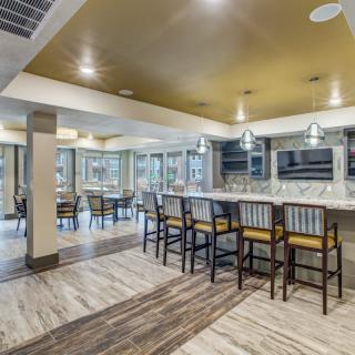 A modern kitchen with a bar area, featuring pendant lighting and sleek countertops.