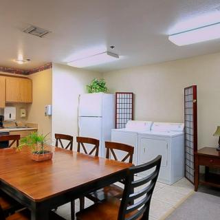 A cozy kitchen and dining area with a wooden table, chairs, and appliances including a refrigerator, washer, and dryer.