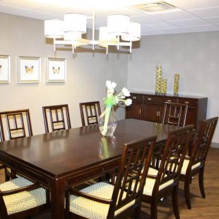 A well-decorated dining room with a large wooden table and chairs set under a modern chandelier.