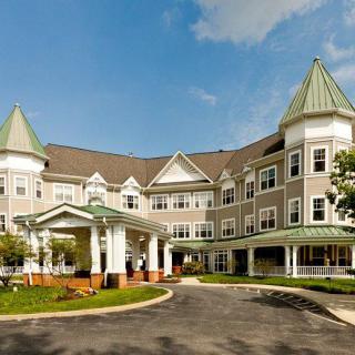 A large, multi-story residential building with distinctive architectural features and a landscaped entrance.