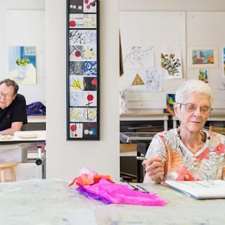 Elderly individuals engaged in an art class, showcasing their creativity in a community setting.