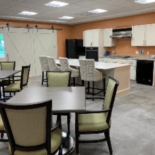 A modern kitchen and dining area with tables, chairs, and a fully equipped cooking space.