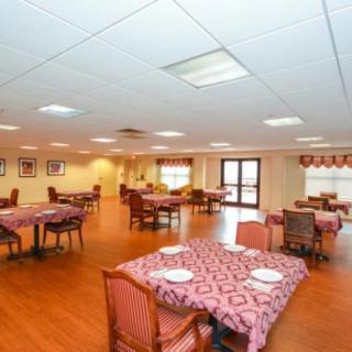An indoor dining room with several tables, each covered with patterned tablecloths and set with plates.