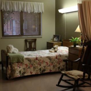 A cozy bedroom with a single bed, rocking chair, and soft lighting.
