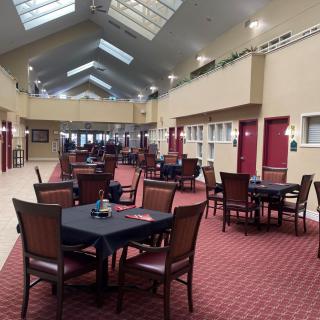 A spacious indoor dining area with multiple tables and chairs, featuring skylights and a carpeted floor.