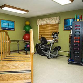 A well-equipped physical therapy room with exercise machines, therapy balls, and weights.