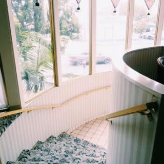 A spiraling staircase with a wooden handrail next to large windows.
