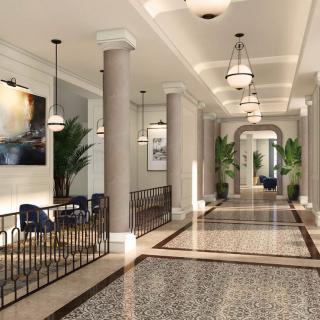 A luxurious, modern hallway with chandeliers, columns, and a stylish seating area.