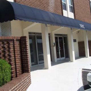 Entrance of a building with a blue awning and brick facade.