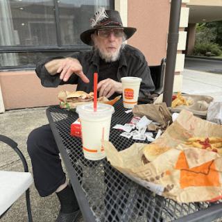 A man enjoying a fast food meal at an outdoor table.