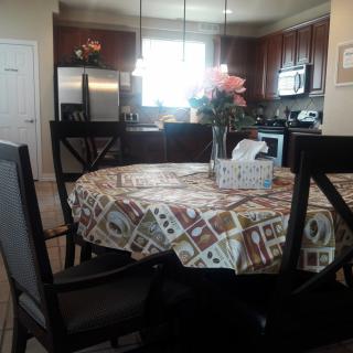 A cozy kitchen and dining area with a patterned tablecloth, flowers, and a tissue box on the table.