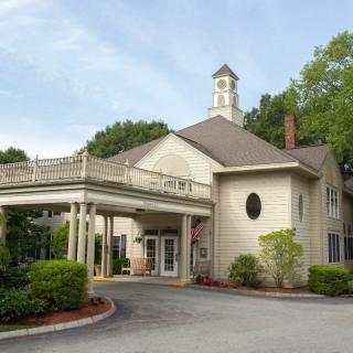 A traditional building with a covered entrance, surrounded by trees and greenery.