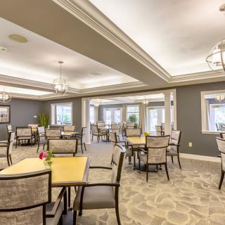 A well-lit dining area with neatly arranged tables and chairs, featuring elegant interior design.