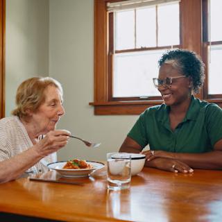 Two women enjoying a meal together, sharing smiles and conversation.