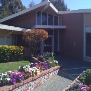 A residential house with a neatly landscaped garden featuring colorful flowers and a brick wall.