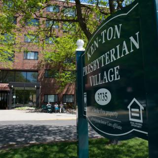 Entrance sign for Ken-Ton Presbyterian Village with a brick building and trees in the background.