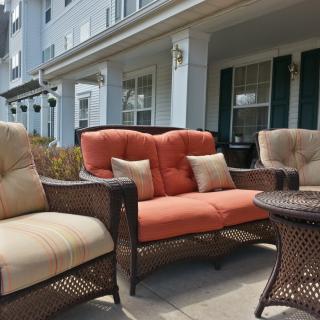 Outdoor patio set with wicker chairs and cushions.