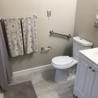 A clean and organized bathroom with a toilet, sink, and towels neatly arranged.