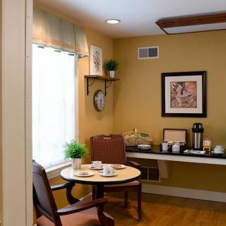 A cozy dining area with a small table, chairs, and a coffee station by the window.