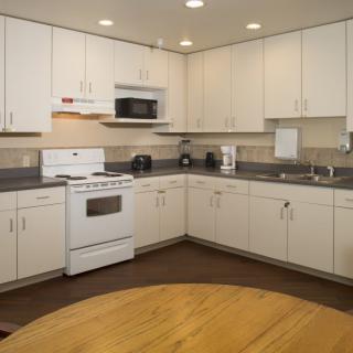 A modern kitchen with white cabinetry and appliances, featuring an oven and microwave.