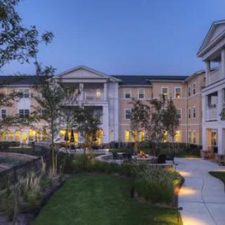 A well-lit residential building with landscaped gardens during the evening.