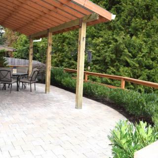 A well-designed patio area featuring a pergola, outdoor seating, and lush garden landscaping.