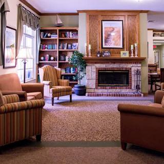 A cozy living room with a fireplace and comfortable armchairs, surrounded by bookshelves.