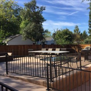 A sunny backyard patio with benches and a surrounding fence.