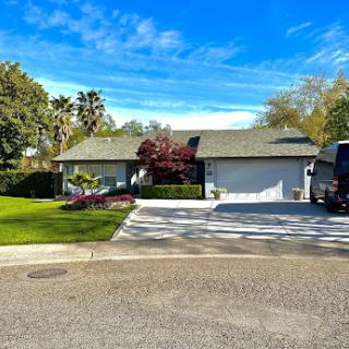 A charming single-story house with a well-maintained front yard and clear blue skies.