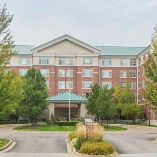 A mid-sized hotel building with a landscaped entrance and surrounding trees.