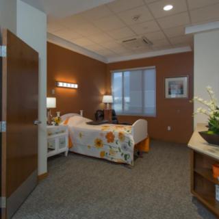 A well-furnished hospital room with a bed, lamps, and a window.
