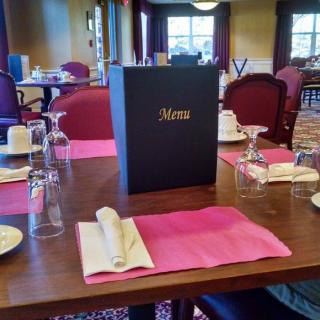 An elegantly set restaurant table with a menu and neatly arranged glassware and napkins.