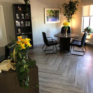 A cozy office space designed for meetings, featuring a round table, comfortable chairs, and greenery.