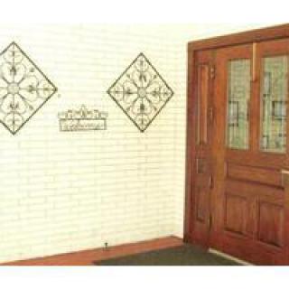 A wooden entrance door with decorative wall art on a brick wall.