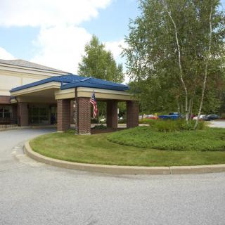 A hospital entrance with an overhang, surrounded by trees and a circular driveway.