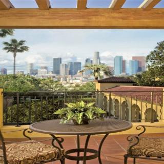 A patio with a table and chairs offers a stunning view of the city skyline in the background.