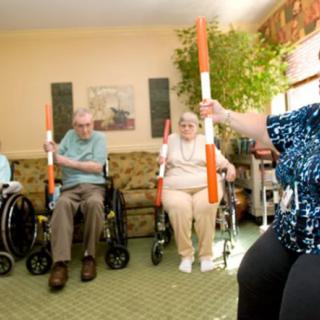 Seniors participating in a group exercise session with orange and white rods.