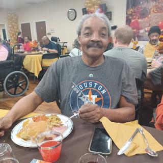 Enjoying a delicious meal with a smile in a community dining setting.