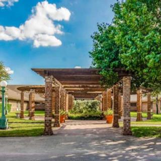 A scenic view of a pergola walkway surrounded by lush greenery and architecture.