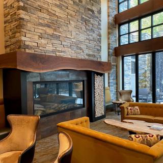 A cozy lounge with a modern stone fireplace and large windows.