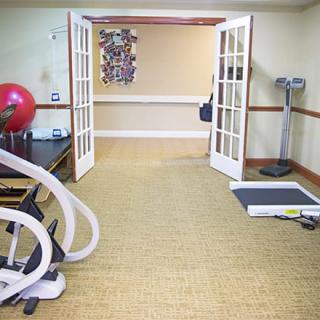 A small gym space equipped with various exercise machines and an exercise ball.