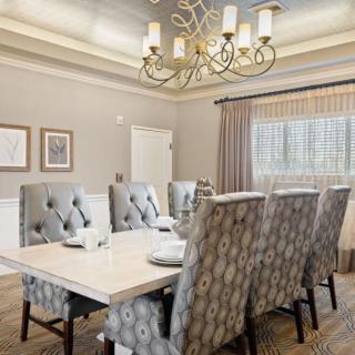 Elegant dining room with a modern chandelier and tufted chairs.