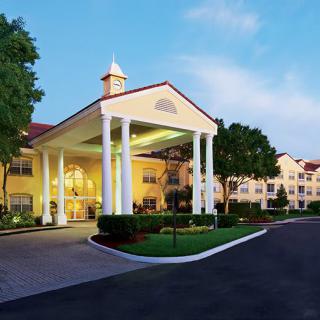 Elegant hotel entrance with large columns and surrounding greenery.