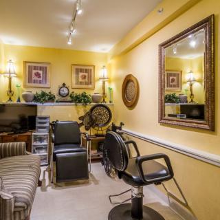 A cozy hair salon with yellow walls, stylish decor, and comfortable seating arrangements.